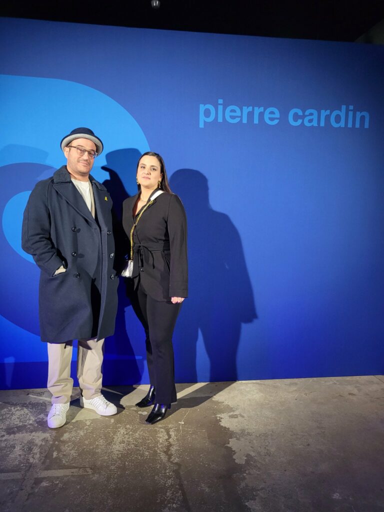 David Lévy et sa femme posant devant un mur bleu portant le nom Pierre Cardin